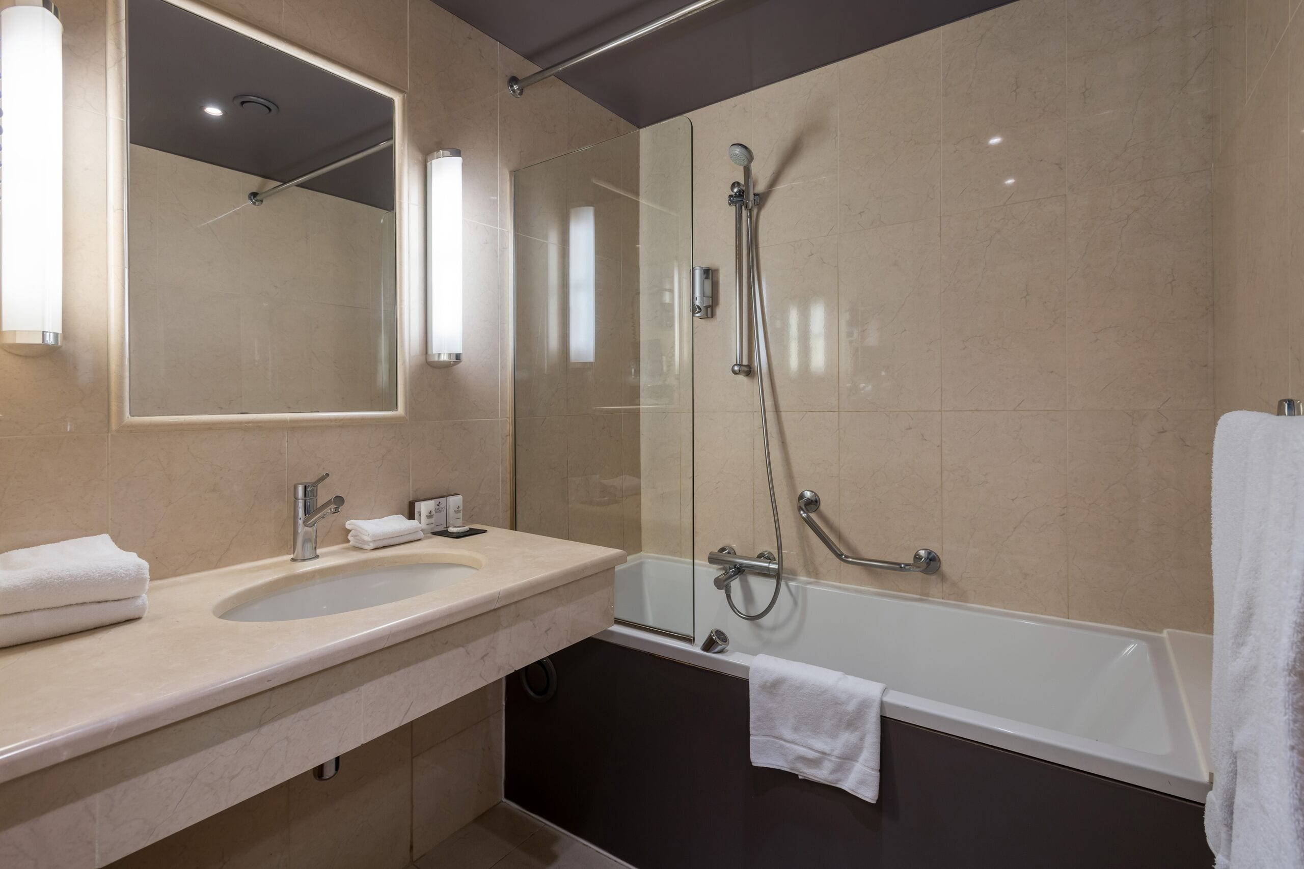 Un baño moderno con ducha de vidrio, una bañera y un tocador con lavamanos y espejo.
