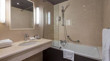 Un baño moderno con ducha de vidrio, una bañera y un tocador con lavamanos y espejo.
