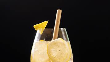Un verre contenant une boisson claire, une tranche de citron et une paille, le tout présenté sur un fond sombre.
