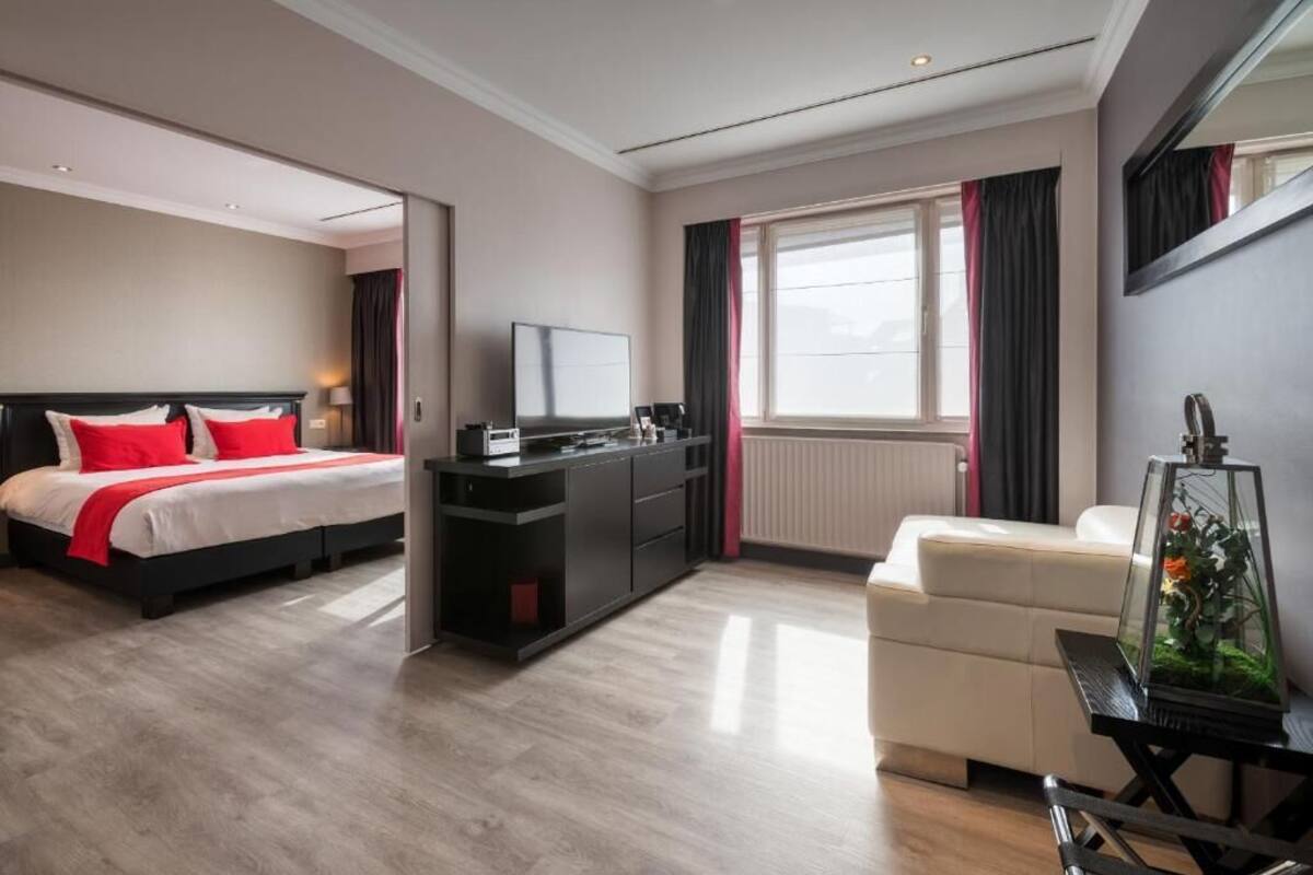 A hotel room with a bed, a desk, a chair, and a large window.