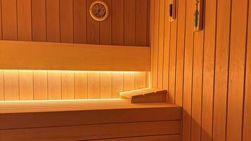 Een houten sauna met banken en een wandheater.