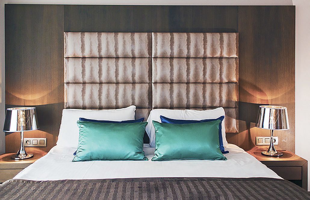 A hotel room with a large bed, two nightstands, and a padded headboard.