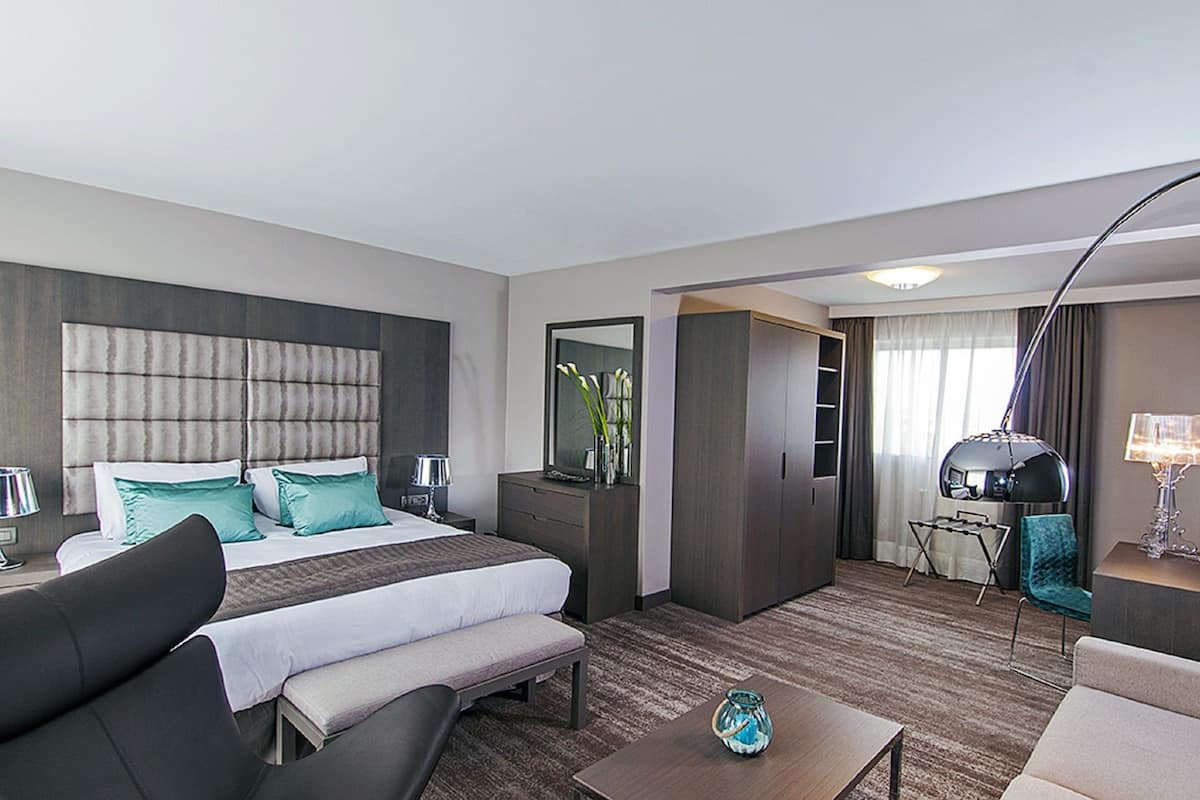 Una habitación de hotel con una cama grande, un escritorio, una silla y un sofá.