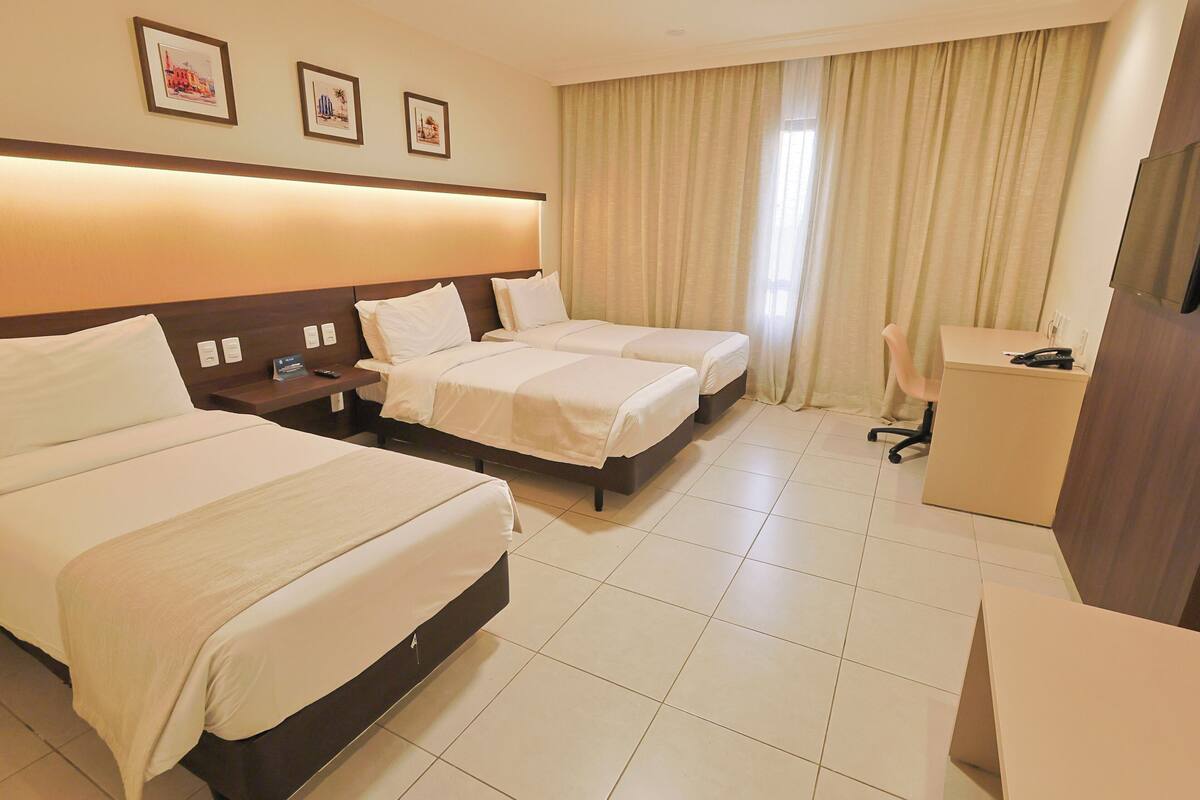 Una habitación de hotel con dos camas, un escritorio, una silla y un televisor.