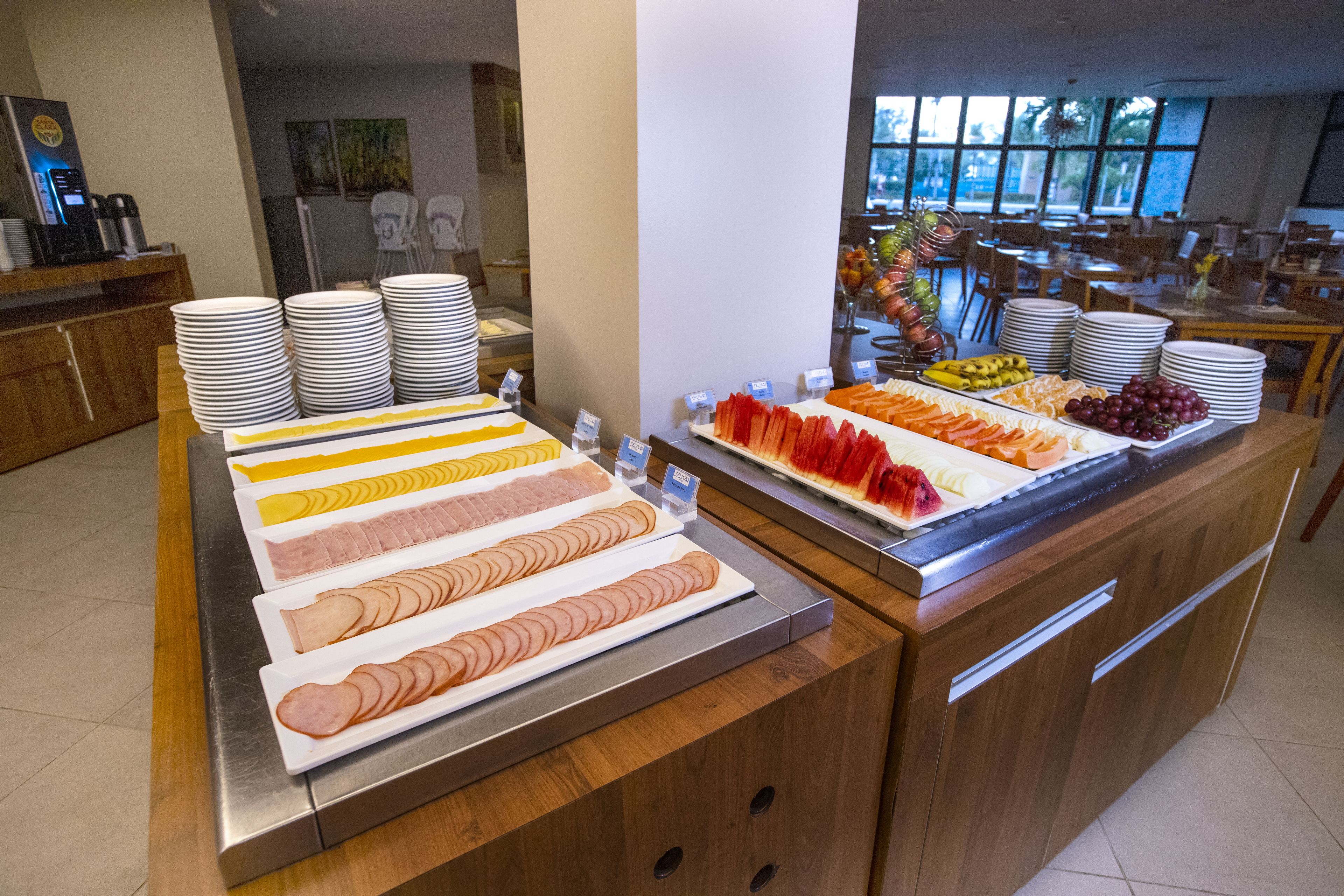 A buffet with various food items and stacked plates.