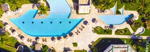 An aerial view of a resort with a large swimming pool, sun loungers, umbrellas, and palm trees. - Del Mar Hotel (Aracaju)