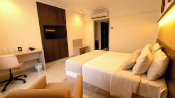 A hotel room with a bed, a desk, a chair, and a television.