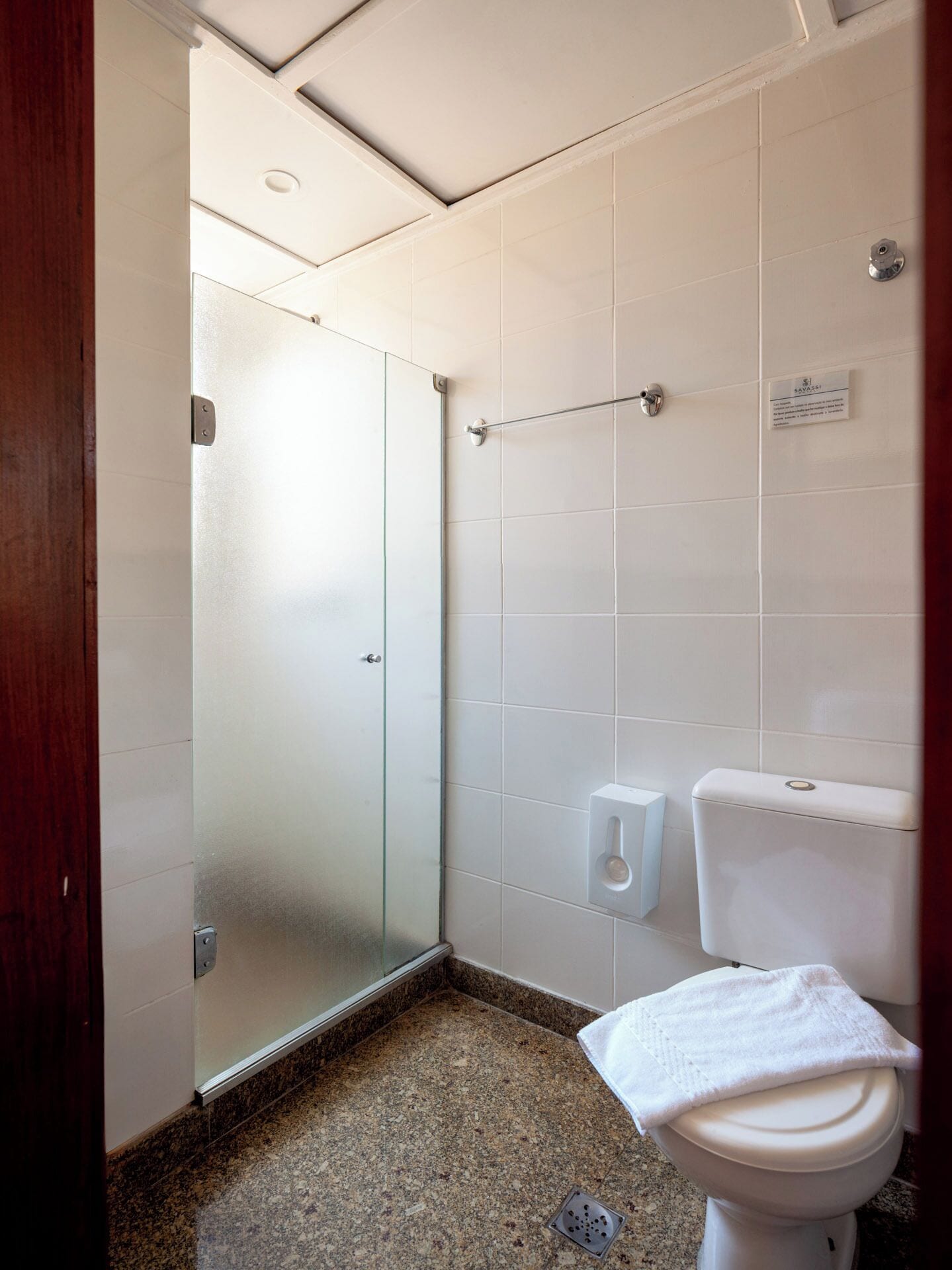 Casa de banho com cabine de duche em vidro, sanita e secador de mãos.