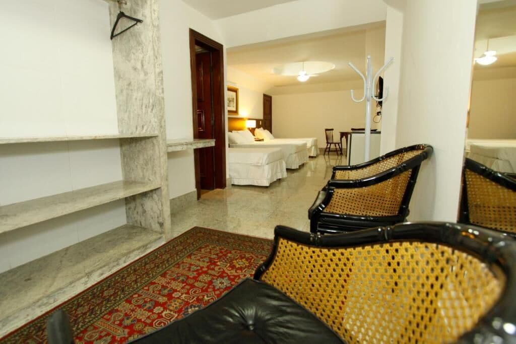 Una habitación de hotel con una cama, una mesita, una silla y un tapete decorativo.