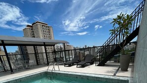 A rooftop pool with clear blue water, surrounded by lounge chairs and a large potted plant. - Savassi Hotel (Belo Horizonte)