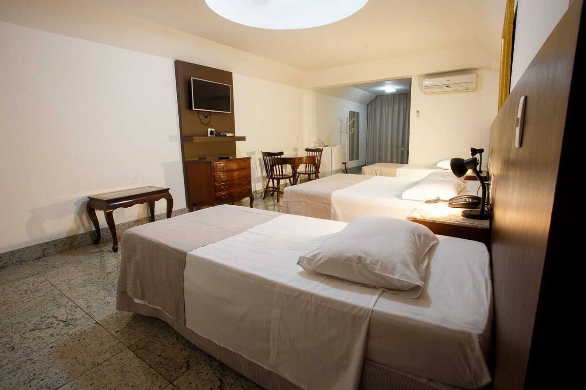 Une chambre d’hôtel avec deux lits, une télévision, un bureau et une chaise.
