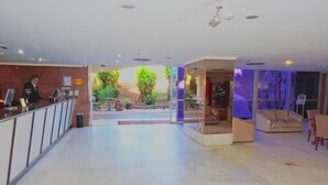 Un hall d’hôtel comprenant un comptoir d’accueil, un espace salon et une vue sur l’extérieur.