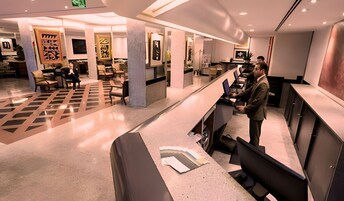 Un moderno vestíbulo de hotel con mostrador de recepción, zona de estar y obras de arte en las paredes.