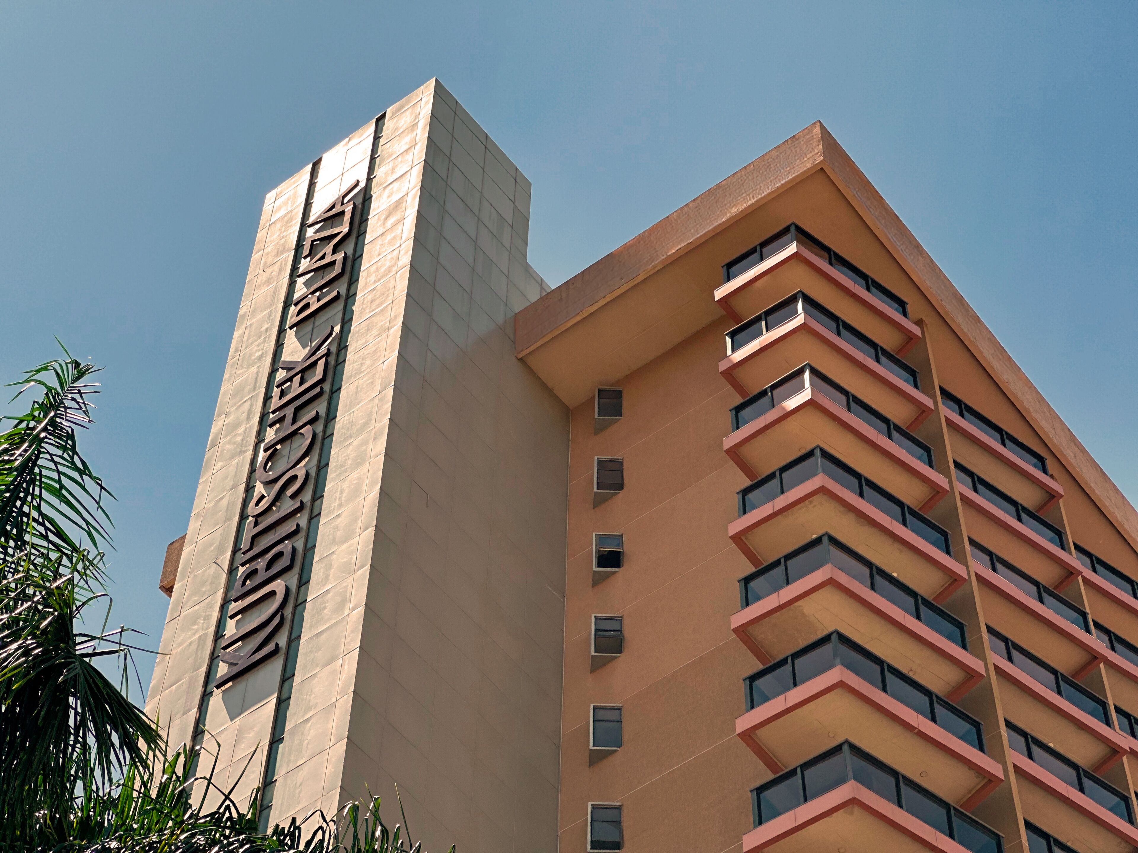 Un immeuble à plusieurs étages, avec une grande enseigne verticale bien visible sur le côté gauche.