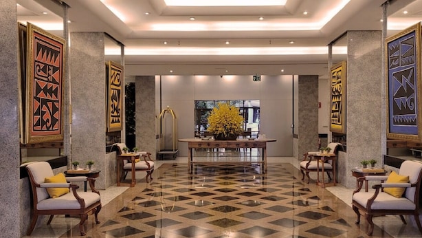 Un hall d’entrée avec un sol à carreaux, une table centrale et des chaises.