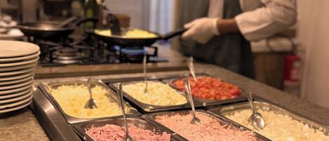 Un buffet proposant une variété de plats, notamment de la viande effilochée, du fromage et d’autres mets.
