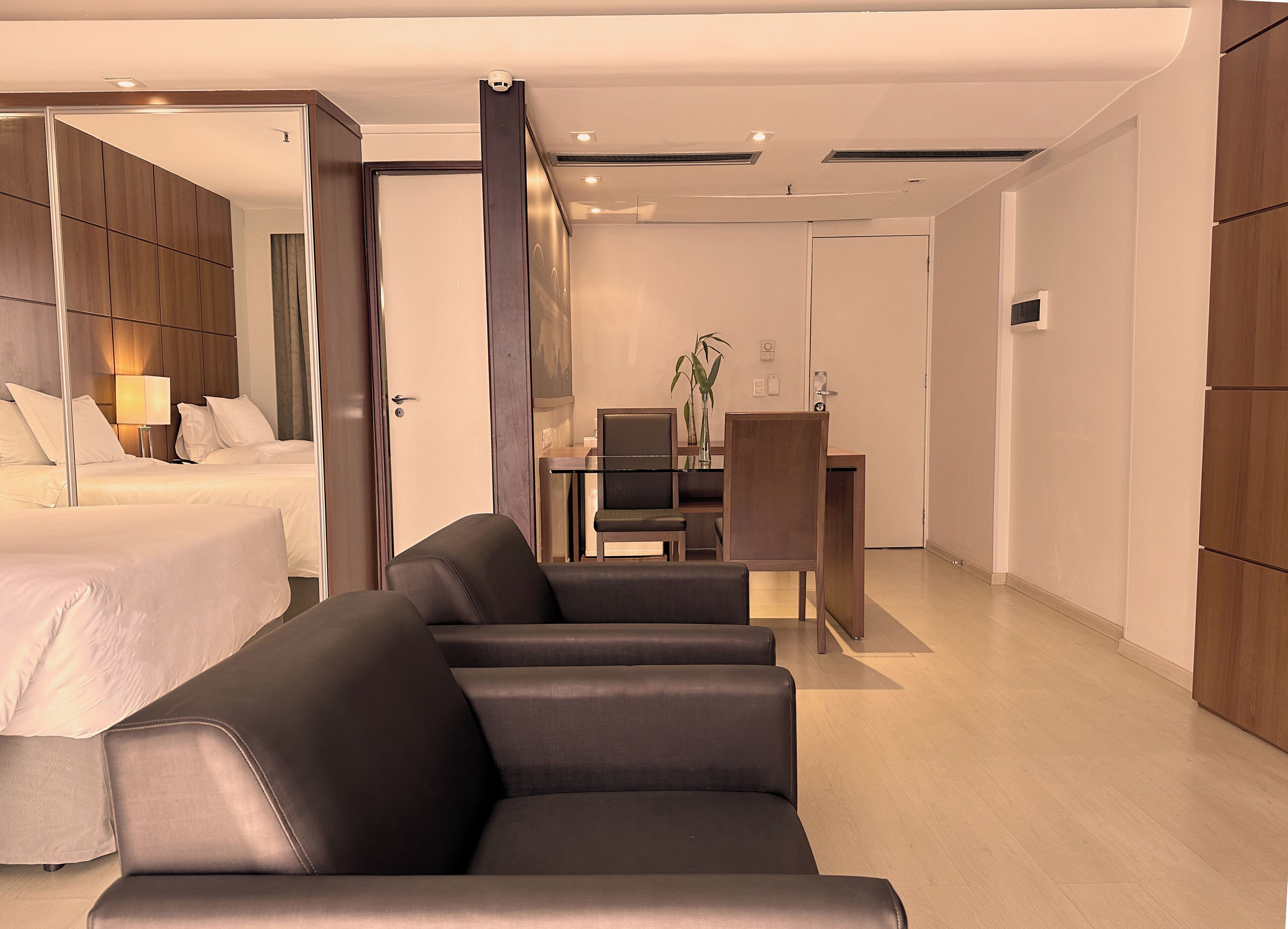 A modern hotel room with a bed, a sofa, a desk, and a TV.
