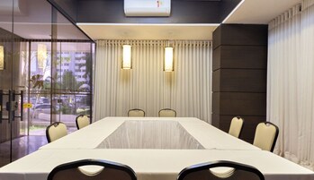 A conference room with a long table, chairs, and a glass partition.
