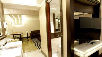 A hotel room with a bathroom, a seating area, and a television.