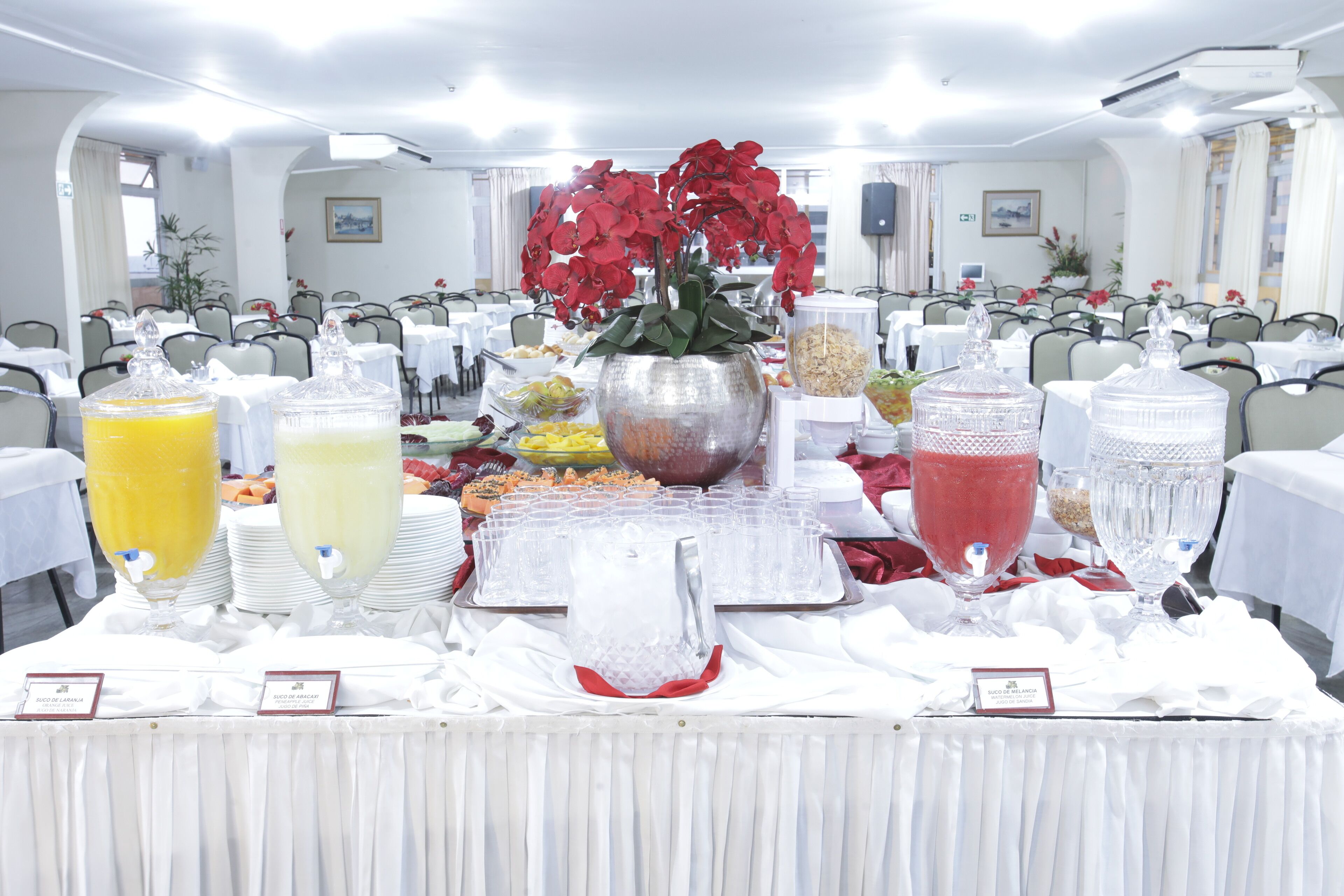 A buffet setup with various food and drink options, including fruit juices and a central floral arrangement.