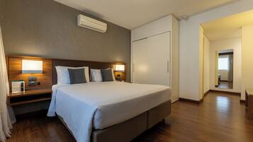 Quarto de hotel com cama grande, abajures, guarda-roupa e espelho.