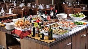 A buffet setup with various food items and wine bottles. - Hotel Deville Curitiba (Curitiba)
