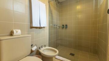 Een badkamer met toilet, bidet en douchecabine met glazen wanden.