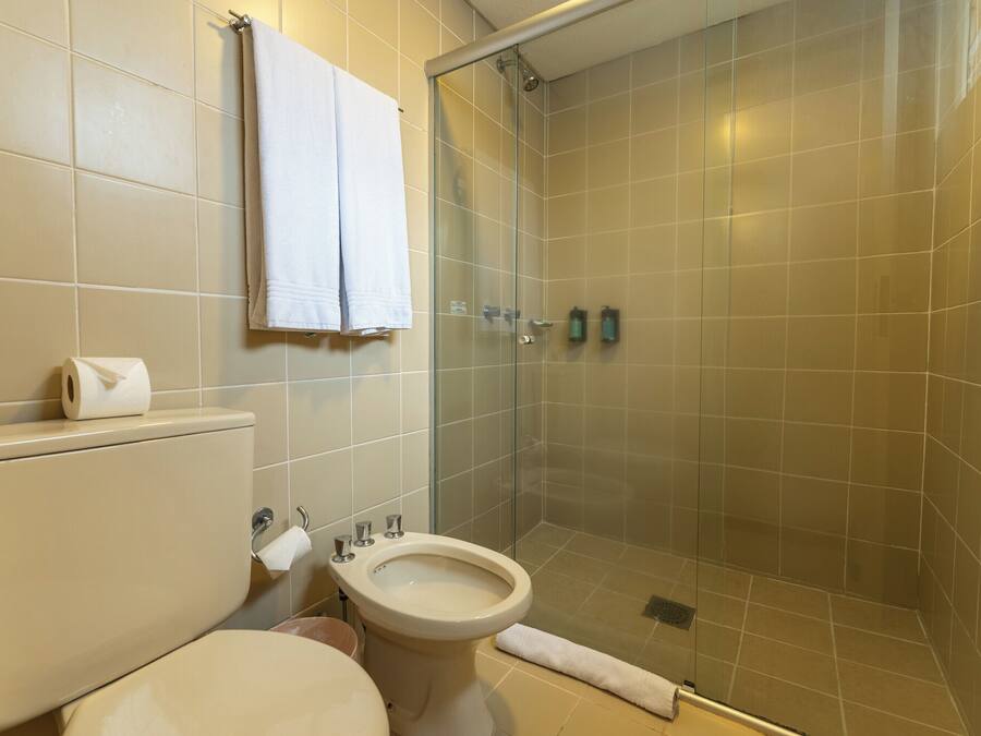 Een badkamer met toilet, bidet en douchecabine met glazen wanden.