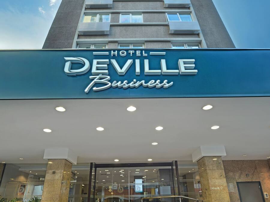 A hotel named "Deville Business" with a modern design, featuring a prominent entrance with steps and a glass facade.