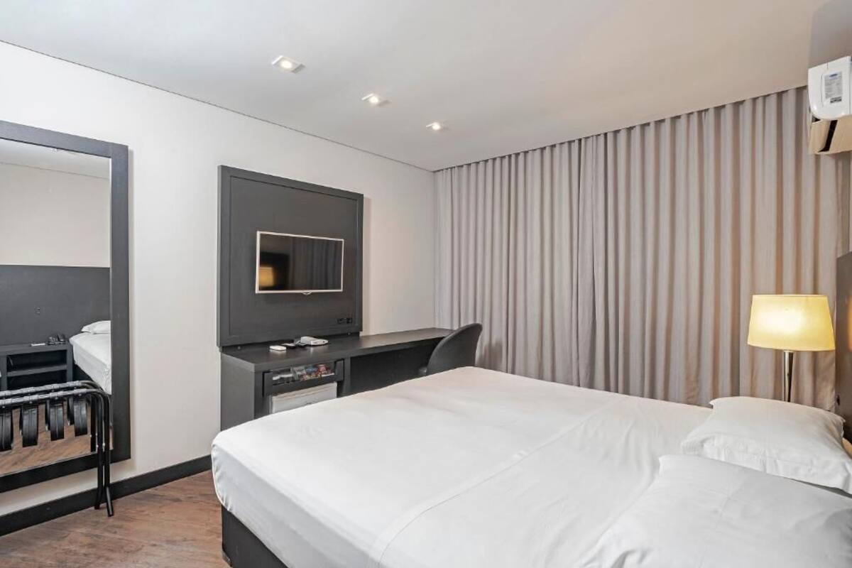 Ett hotellrum med en säng, ett skrivbord, en stol, en tv och en garderob.