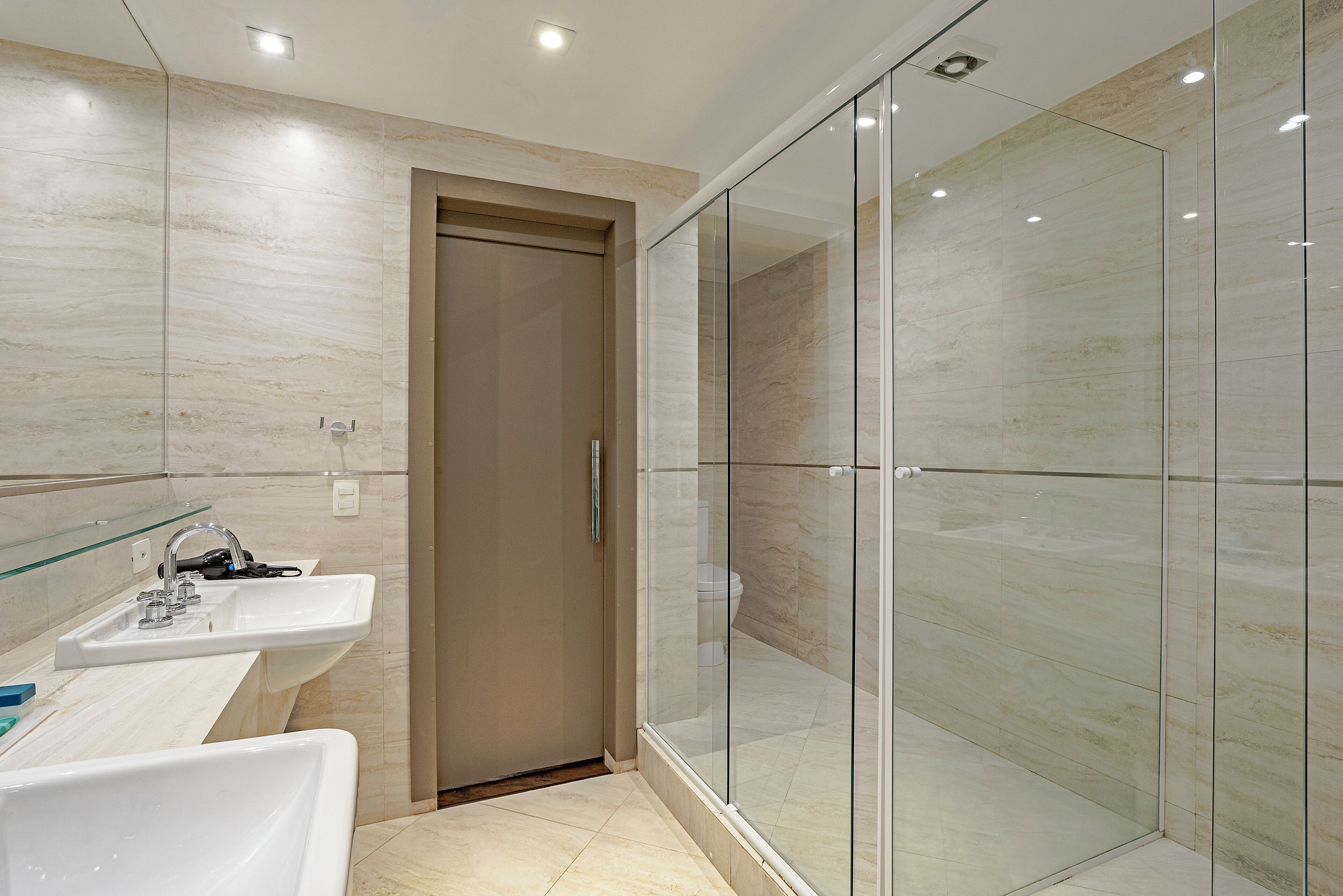 A modern bathroom with a glass shower enclosure, a sink with a mirror, and a toilet.