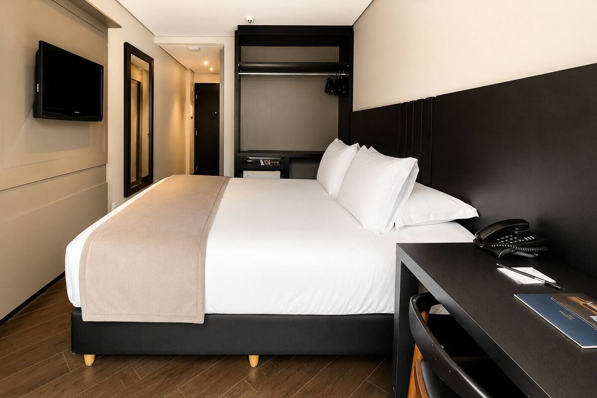 Ett hotellrum med en säng, ett nattduksbord, en tv och en rymlig klädkammare.