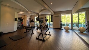 A modern gym with exercise equipment, large windows, and a wooden floor. - Slaviero Baía Norte Florianópolis (Florianópolis)