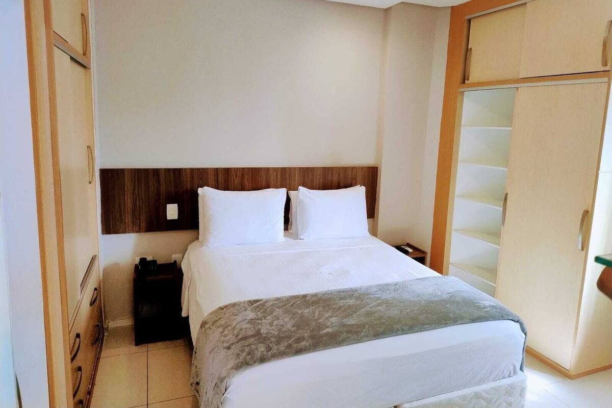 A hotel room with a bed, a wardrobe, and a nightstand.