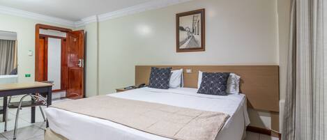 A hotel room with a bed, a desk, and a chair.