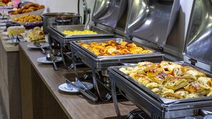 Un bufé con distintos alimentos presentados en fuentes de metal.