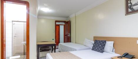 A hotel room with two beds, a desk, and a bathroom visible through an open door.