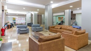 Un vestíbulo amplio con sofás de cuero, un mostrador de recepción y una escalera.