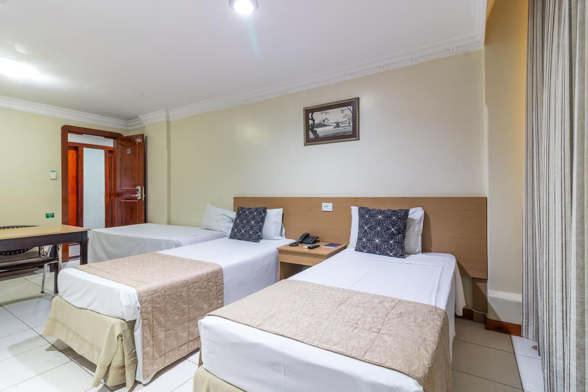Ett hotellrum med två separata sängar, ett skrivbord och en stol.