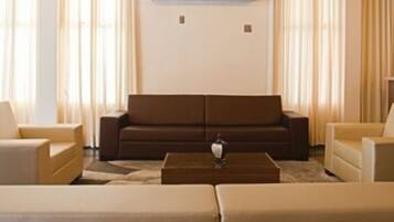 Ein modernes Wohnzimmer mit einem braunen Sofa, beigen Sesseln und einem Couchtisch.
