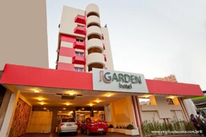 A hotel named 'Garden Hotel' with a modern design, featuring a prominent red and white facade, multiple balconies, and a well-lit entrance. - Oft Garden Hotel (Goiania)