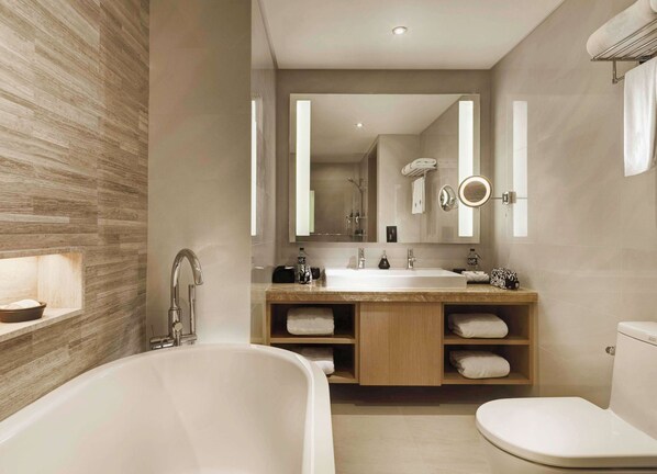 A modern bathroom with a freestanding bathtub, a sink with a mirror, and a toilet. - Banyan Tree Bangkok (Bangkok)