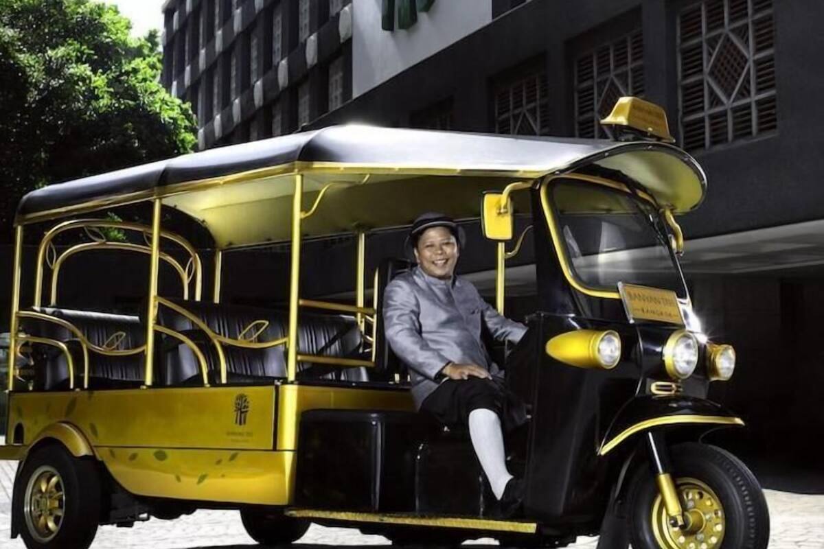 A yellow and black vintage-style vehicle parked in front of a building with a large green sign.