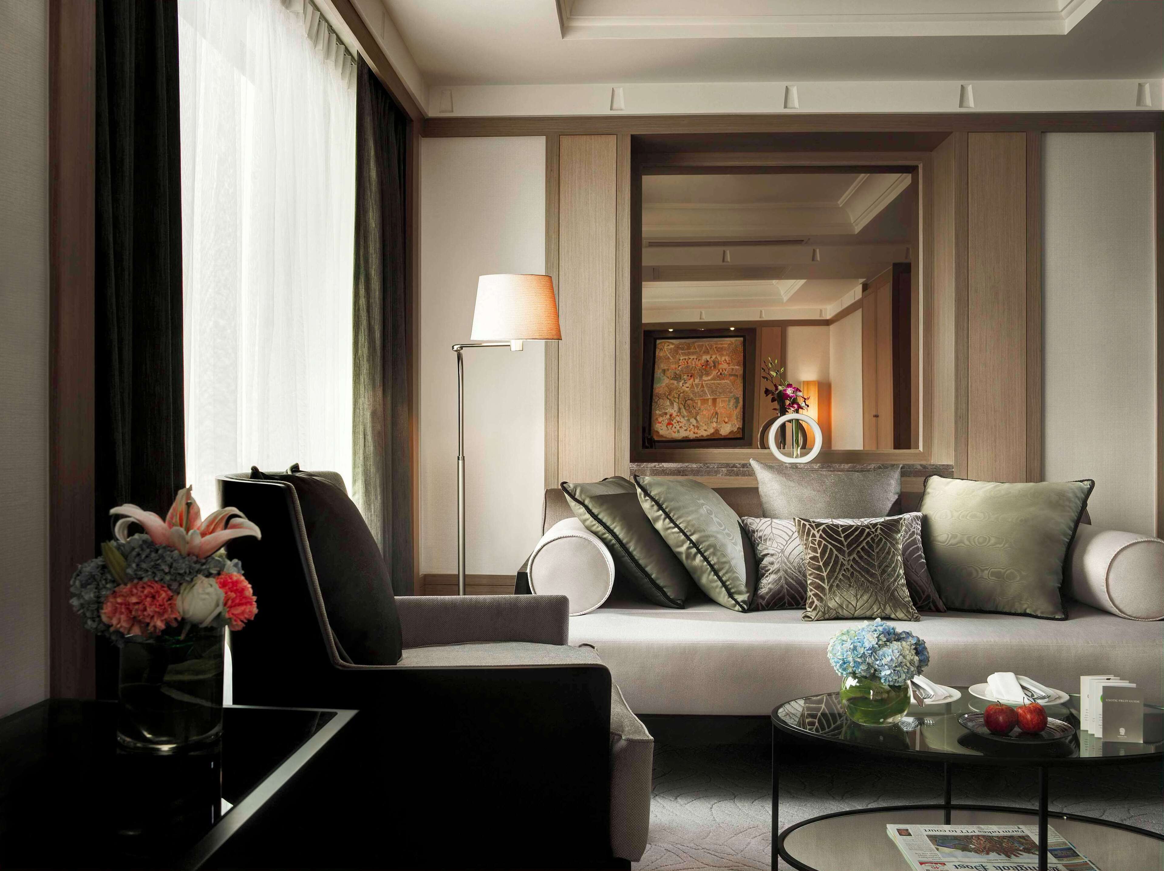 A modern living room with a sofa, a floor lamp, a vase with flowers, and a coffee table with a newspaper.