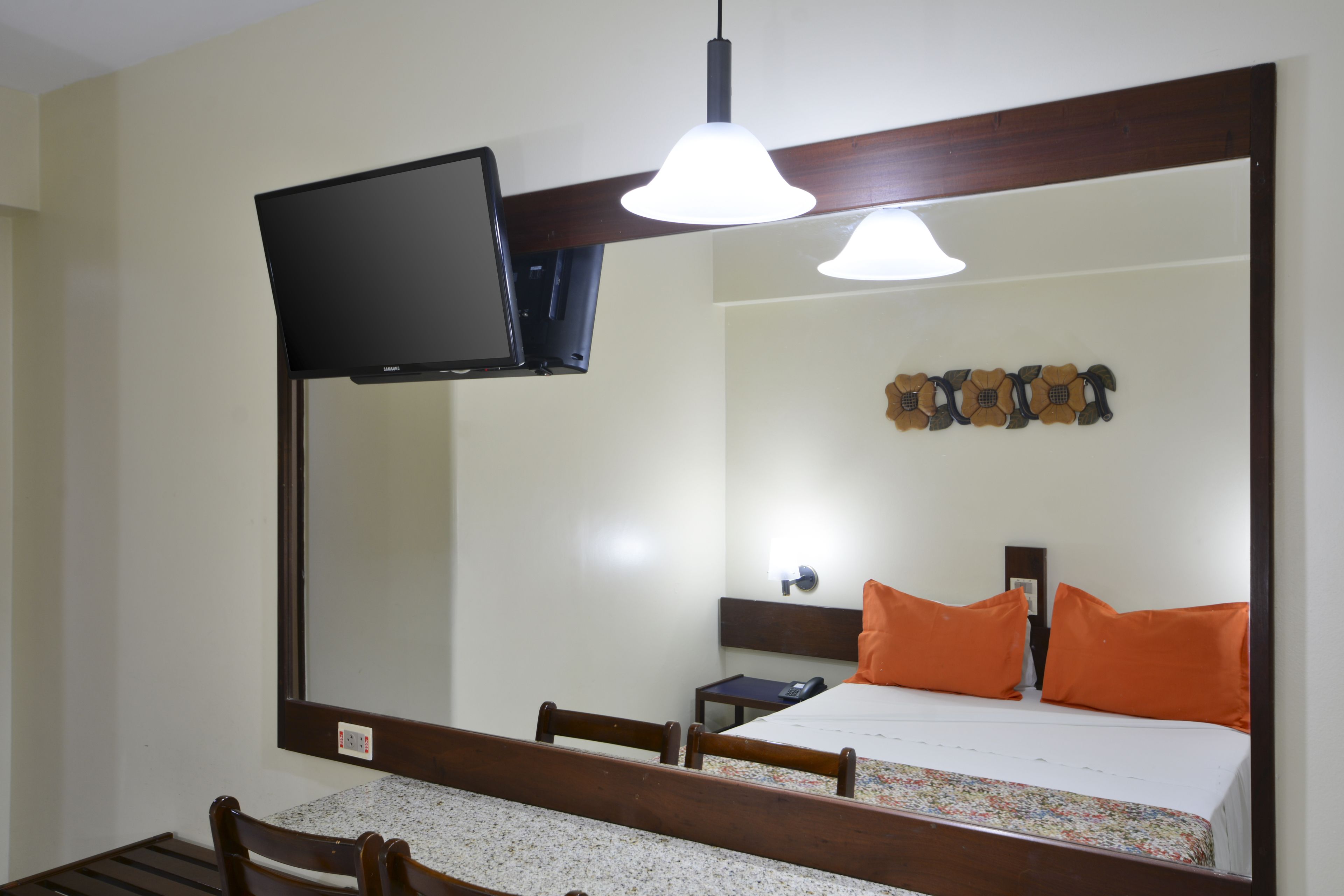 A hotel room with a bed, a television mounted on the wall, a desk, and a chair.