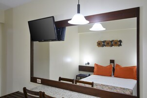 A hotel room with a bed, a television mounted on the wall, a desk, and a chair.