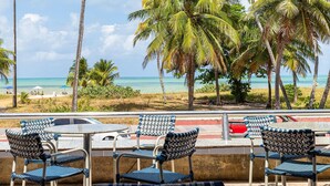 A beachside café with outdoor seating, palm trees, and a view of the ocean. - Littoral Hotel (João Pessoa)