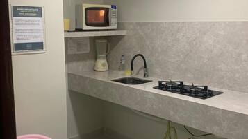Una kitchenette compacta con microondas, lavamanos y estufa a gas.