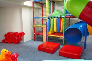 A play area with a climbing net, colorful slides, and red hexagonal structures.