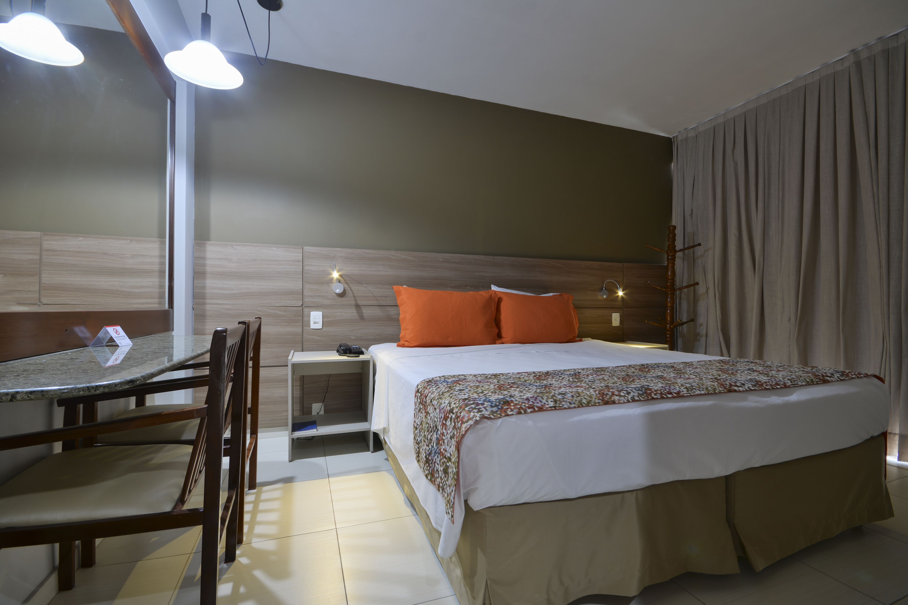 A hotel room with a bed, a desk, and chairs.